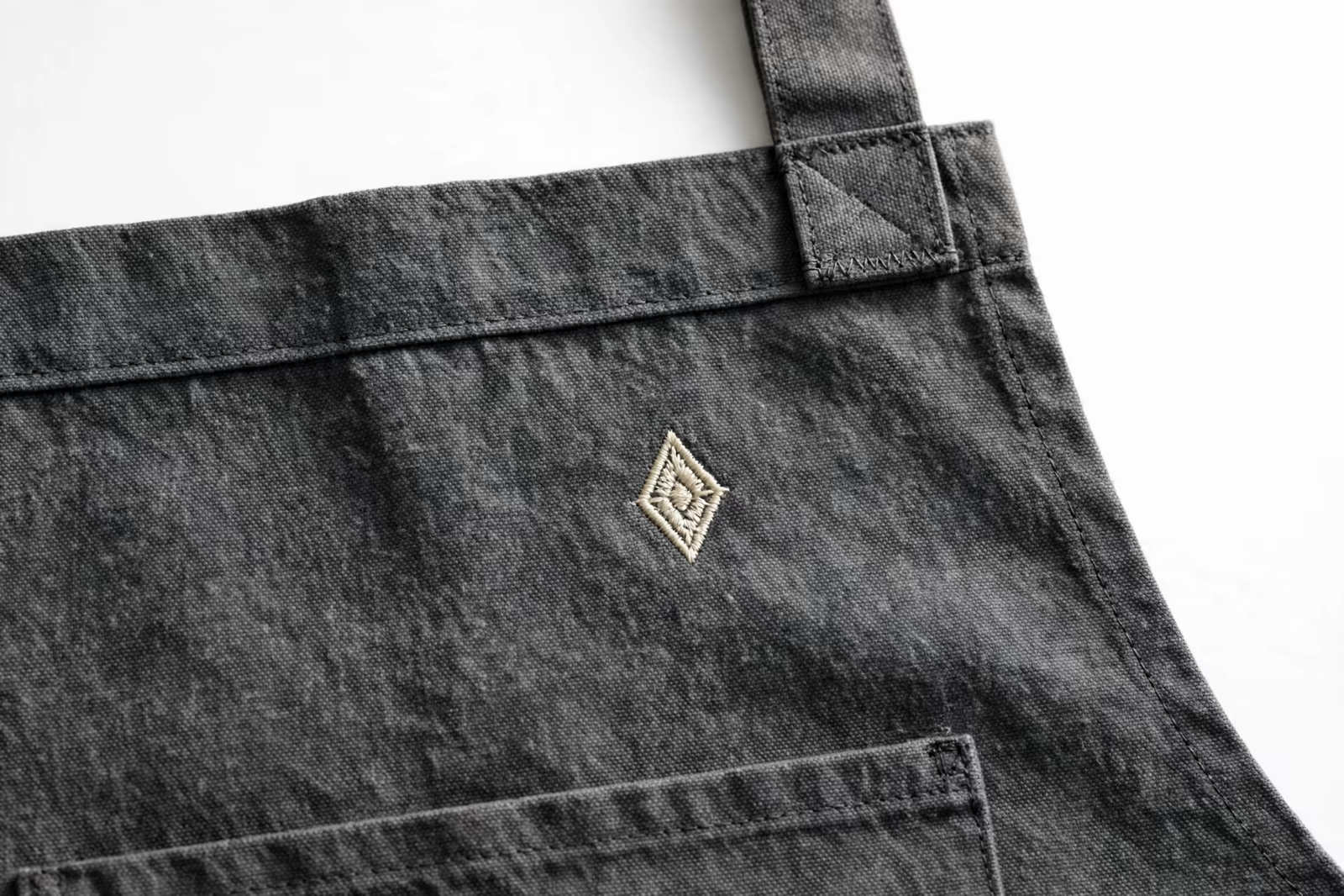 Embroidered motif on the chest of a charcoal apron from a manufacturer in Bangladesh