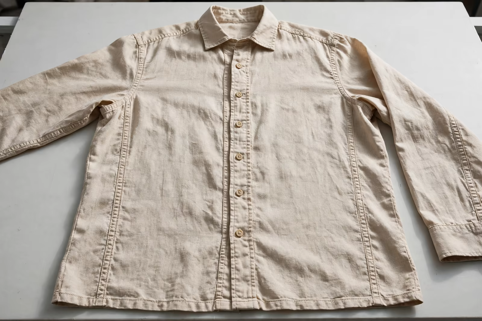 A sample shirt laid flat on an evaluation table showing its seams and stitching, produced by a clothing manufacturer in Bangladesh