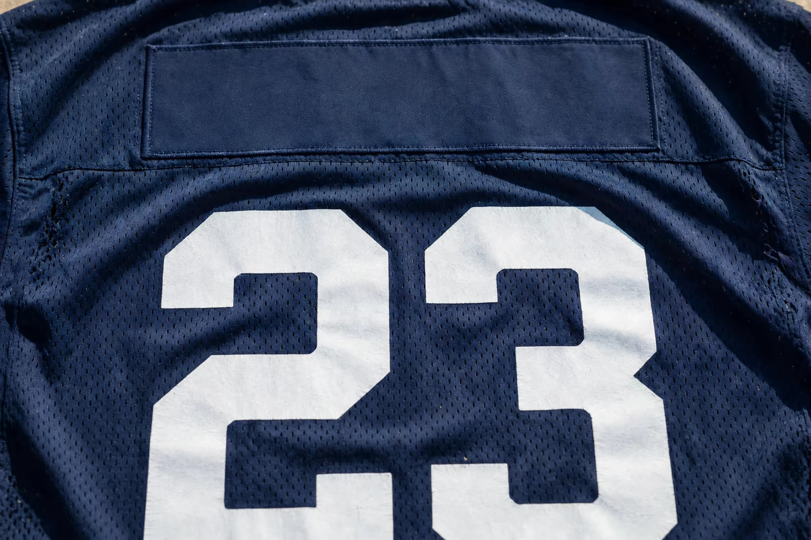 The back of a mesh team shirt with a large printed number and a blank name panel, produced by a clothing manufacturer in Bangladesh